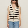 A woman wears the Sanctuary Clothing textured sweater vest macrame black stripe 3, paired with black sunglasses and light blue jeans, standing against a plain light background.