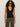 A woman with curly hair wears dark sunglasses and the Sanctuary Clothing knitted button front black top, paired with olive green pants, standing against a plain light background.
