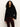 A woman with long curly hair wears the Sanctuary Clothing forever cashmere popover in black, paired with dark red corduroy pants, standing against a plain light background.