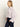 A woman with straight blonde hair stands in profile against a light background, wearing the Sanctuary Clothing forever cashmere popover in light twilight mauve and dark high-waisted jeans.