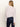 A woman with long blonde hair is shown from the back, wearing Sanctuary Clothing’s forever cashmere popover in light twilight mauve and dark blue pants against a plain, light background.