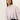 A young woman with straight, light brown hair models the Sanctuary Clothing forever cashmere popover in light twilight mauve, paired with dark pants. She poses against a plain, light background with a neutral expression, gazing slightly away.