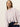 A young woman with straight, light brown hair models the Sanctuary Clothing forever cashmere popover in light twilight mauve, paired with dark pants. She poses against a plain, light background with a neutral expression, gazing slightly away.
