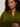 A person with curly dark hair wears the must have cardi in martini olive by Sanctuary Clothing, paired with gold hoop earrings and a gold ring with a dark stone, standing against a plain light background.
