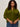 A woman with curly dark hair wears the Sanctuary Clothing must have cardi in martini olive and blue jeans, standing against a plain light background. She looks at the camera with a neutral expression.