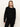 A woman with straight, light brown hair wears the must have cardi black from Sanctuary Clothing and black pants, standing against an off-white background and looking at the camera with a neutral expression.