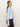 A woman with long, light brown hair in a ponytail models the Sanctuary Clothing must have cardi blue powder, standing sideways and looking at the camera against a plain light background.