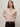 A woman with straight, light brown hair models the Sanctuary Clothing "must have cardi" in heather rose, styled with dark pants and a brown belt, standing against a plain light background with her hands behind her back.