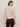 A woman with light brown hair wears the Sanctuary Clothing must have cardi in heather rose, standing with her back to the camera against a light beige background.