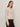 A woman with light brown hair wears the Sanctuary Clothing "must have cardi" in heather rose, paired with dark high-waisted pants, standing against a plain light background and looking slightly to the side with a neutral expression.