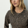 A woman with long blonde hair models the "must have cardi french kitty" leopard print button-up sweater by Sanctuary Clothing, standing against a light background and looking slightly to the side.
