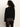 A person with curly dark hair, seen from behind against a plain light background, wears the Sanctuary Clothing zip it sweater in black and shiny black pants.