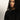 A woman with curly black hair and medium skin tone wears the Sanctuary Clothing zip it sweater in black, gazing thoughtfully to her left against a plain, light background.