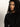 A woman with curly black hair and medium skin tone wears the Sanctuary Clothing zip it sweater in black, gazing thoughtfully to her left against a plain, light background.