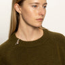 A woman with straight blonde hair wears the Sanctuary Clothing zip it sweater dirty martini, featuring a zip collar, against a plain background with a neutral expression.