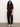 A woman with long curly hair wears the Sanctuary Clothing perfect sweater tee in chicory, paired with black cargo pants and white sneakers. She stands against a plain light-colored wall with her hands in her pockets.