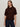 A woman with long, straight brown hair wears the Sanctuary Clothing perfect sweater tee in dark crimson and dark blue jeans, standing against a plain light-colored background.
