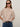 A woman with straight light brown hair and a neutral expression wears Sanctuary Clothing's perfect sweater tee fawn, dark sunglasses, blue jeans with a black belt, standing against a plain light background.