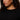 A person with curly hair wears the Sanctuary Clothing ribbed sweater tee in black (extended sizing), paired with large gold hoop earrings, looking slightly to the side in a closely cropped upper torso and face image.
