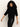 A woman with curly hair wears the Sanctuary Clothing ribbed sweater tee in black and black leather pants while looking down against a plain, light background.