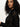 A woman with curly dark hair wears the Sanctuary Clothing boheme popover black sweater, looking slightly over her shoulder against a plain light background.