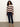 A woman with curly hair models the Sanctuary Clothing 24 7 popover in chicory light oat, styled with dark blue cropped jeans and tan loafers, standing against a plain light-colored wall.