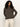 A person with curly dark hair wears the Sanctuary Clothing 24 7 Popover French Kitty top with light-colored pants, standing against a plain off-white background and showing a relaxed expression.