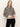 A woman with long, straight blonde hair wears the Sanctuary Clothing "soft touch popover spots" sweater—beige with black leopard print—and black pants, standing against a plain light background with a neutral expression.