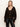 A woman with straight, blonde hair wears the meow cardi kitty camo leopard print cardigan by Sanctuary Clothing over a black top and leather pants, posing against a plain white background.
