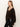 A woman with long, straight, light brown hair wears the Sanctuary Clothing meow cardi kitty camo—a brown and black animal print cardigan—over a black top with black leather pants, standing against a plain light background.