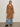 A woman with straight, shoulder-length hair and a neutral expression stands against a plain background wearing the Sanctuary Clothing Aria Wrap Coat in camel over light blue jeans and black ankle boots.