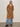 A woman stands against a plain background, wearing the Aria Wrap Coat Camel by Sanctuary Clothing over a white top, blue jeans, and black ankle boots, with her hands in her pockets.